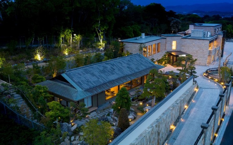 A modern Japanese-style house with a beautiful garden illuminated at night.
