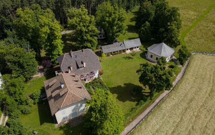 Aerial view of a countryside property with several buildings, trees, and surrounding fields.