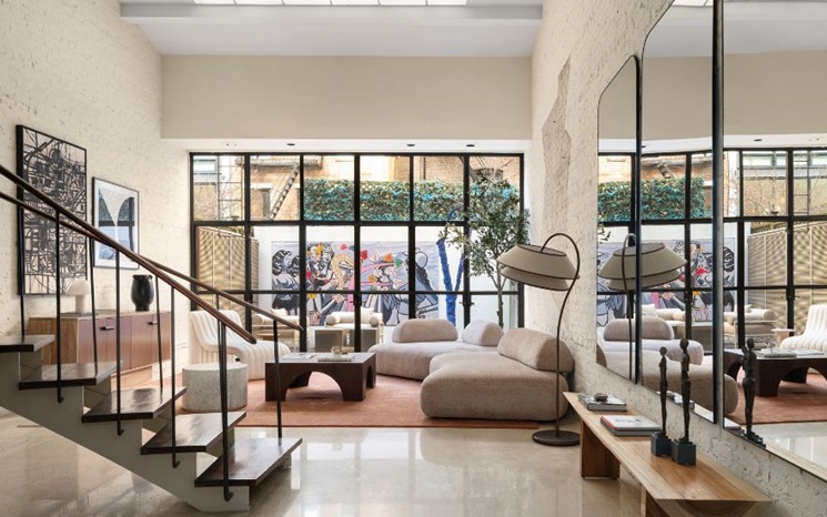 Modern living room with cozy furniture, large windows, and wall art visible through the glass.