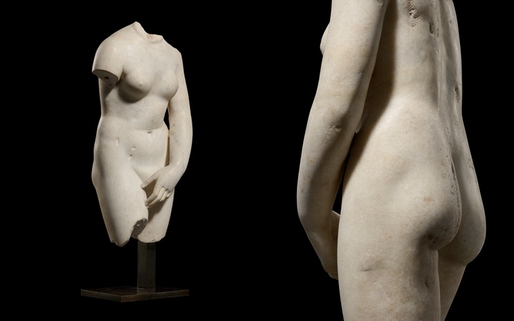 A headless and armless marble statue of a nude female torso is shown from the front and back on a black background.