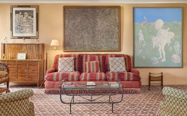 A cozy living room with a red striped sofa, art-filled walls, and patterned carpet.