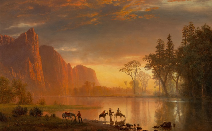 Riders and horses gather by a serene river at sunset, with mountains and trees in the background.