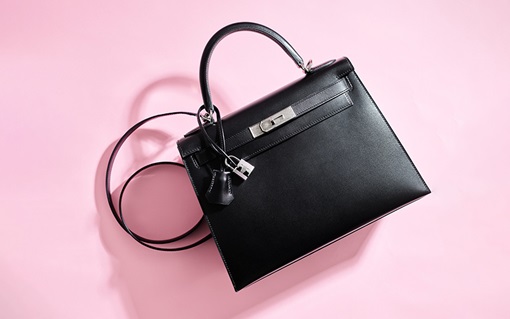 A luxury crocodile leather handbag with a top handle and silver hardware.