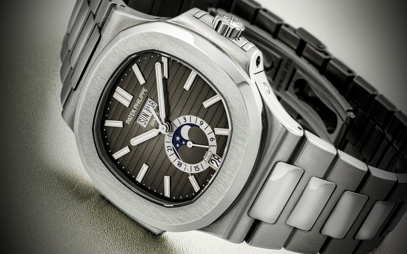 A luxury stainless steel watch with a moonphase and date display on a dark dial.