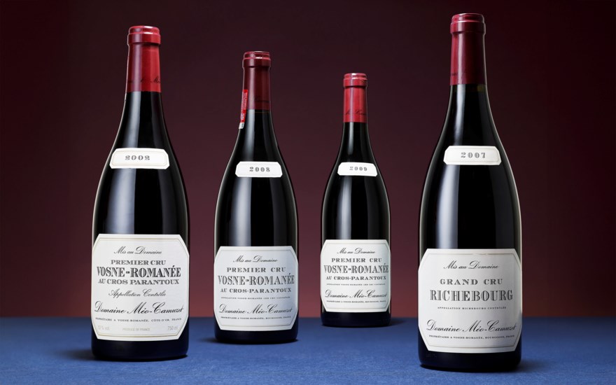 Four bottles of French red wine with labeled vintages are displayed against a dark background.