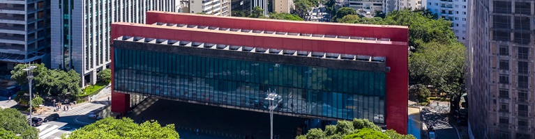A large modern building with red columns and glass walls in an urban city setting.