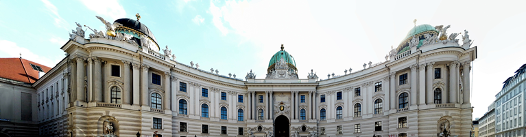 Panoramic view of a grand, ornate building with intricate sculptures and a domed roof.