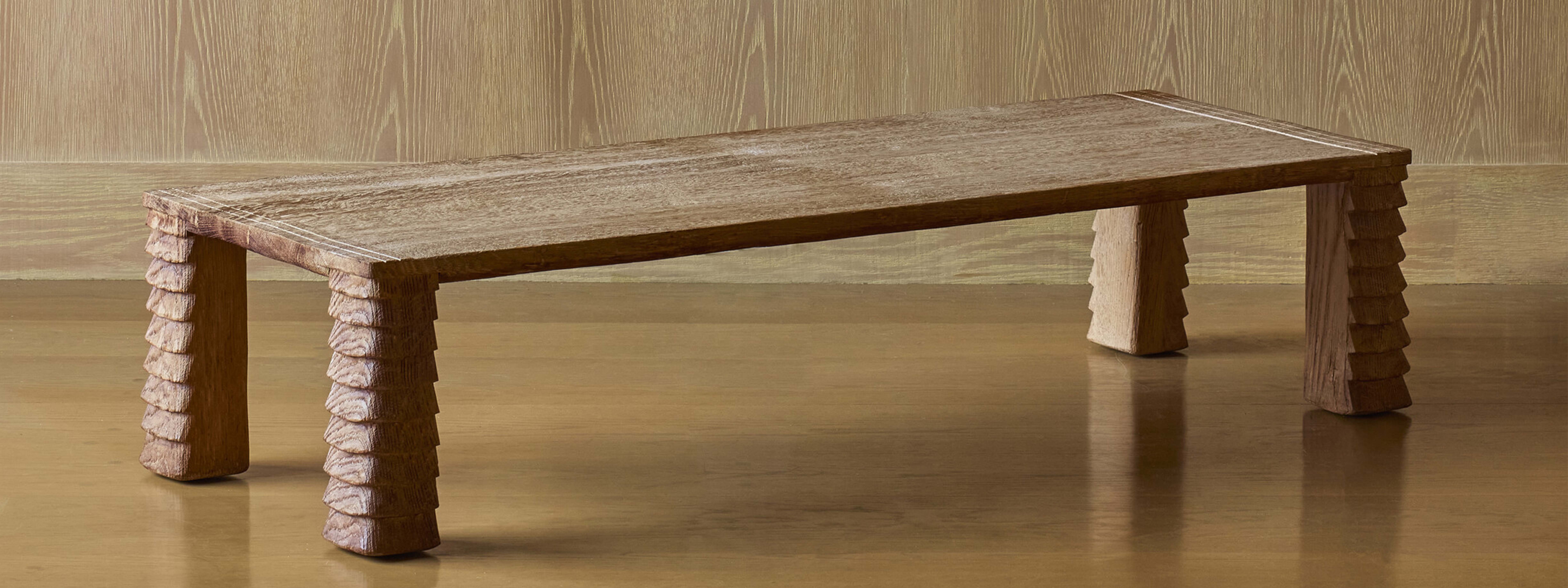 A wooden table with textured legs against a wooden background.