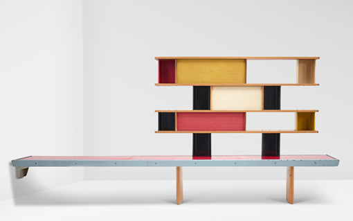 A modernist bookshelf features colorful horizontal sections in red, yellow, and black, with a minimalist bench attached below.