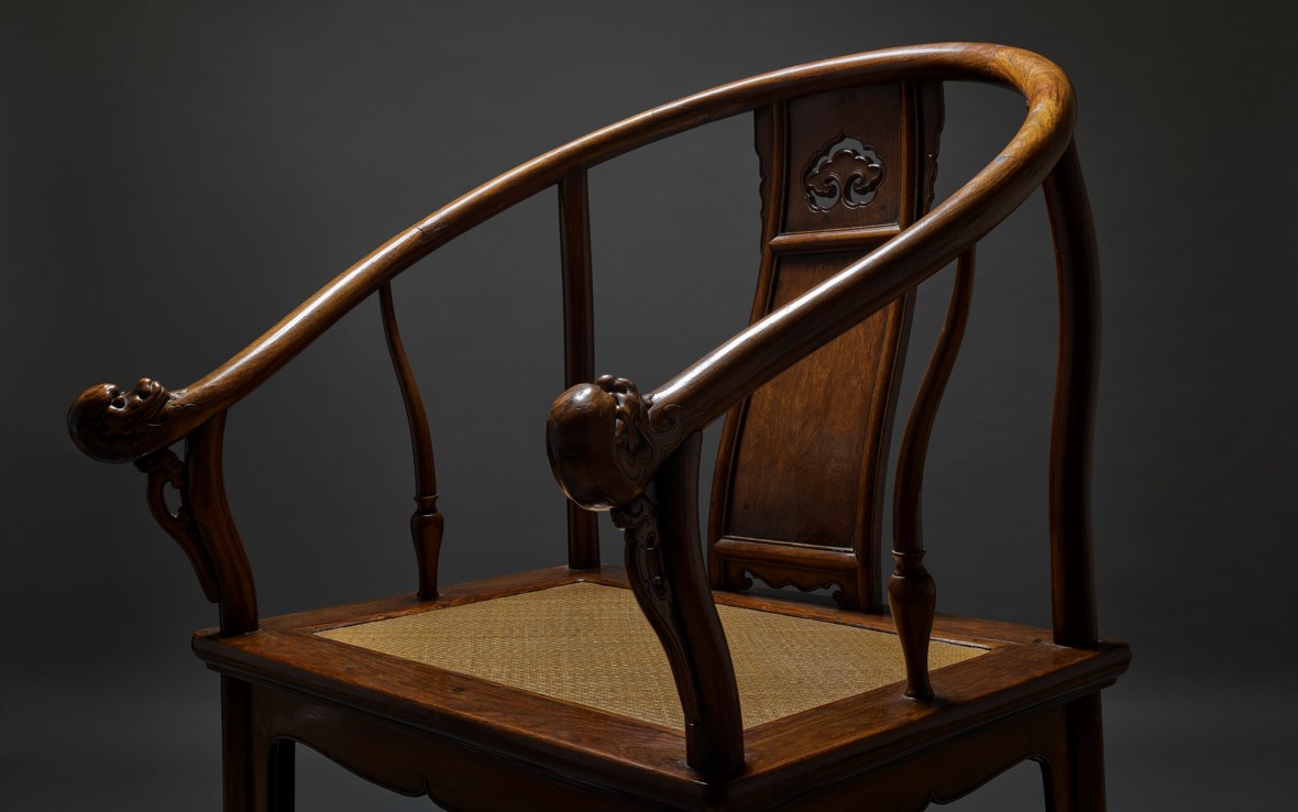 A traditional wooden chair with curved armrests and intricate carvings. | A traditional wooden chair with curved arms and intricate carvings on the backrest.