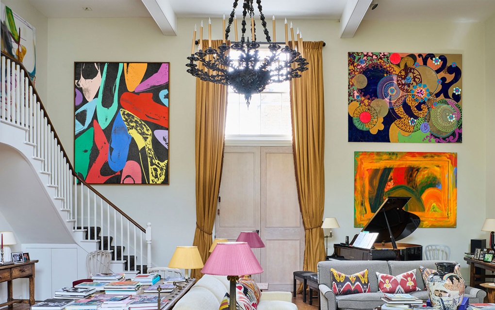 A brightly lit living room with colorful abstract art, a grand piano, and eclectic decor.