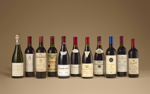 A selection of eleven assorted wine bottles is displayed against a plain beige background.