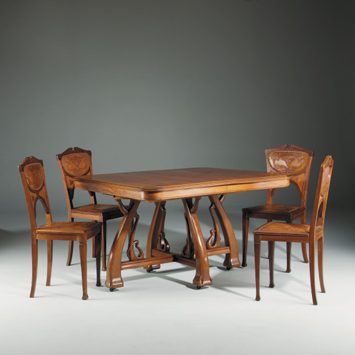 AN ART NOUVEAU CARVED DINING TABLE AND SIX CHAIRS ENSUITE , DESIGNED BY