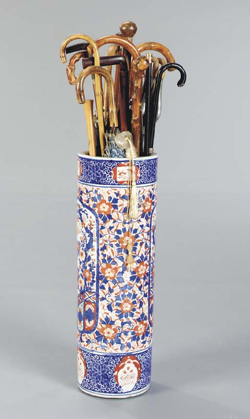 A CERAMIC UMBRELLA STAND WITH AN ASSORTMENT OF CANES AND UMBRELLAS