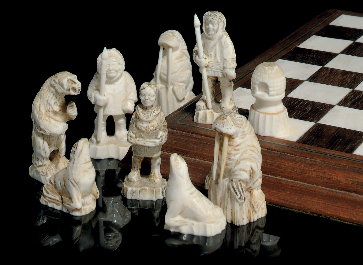 AN ARCTIC CIRCLE CARVED WALRUS IVORY FIGURAL CHESS SET AND BOARD