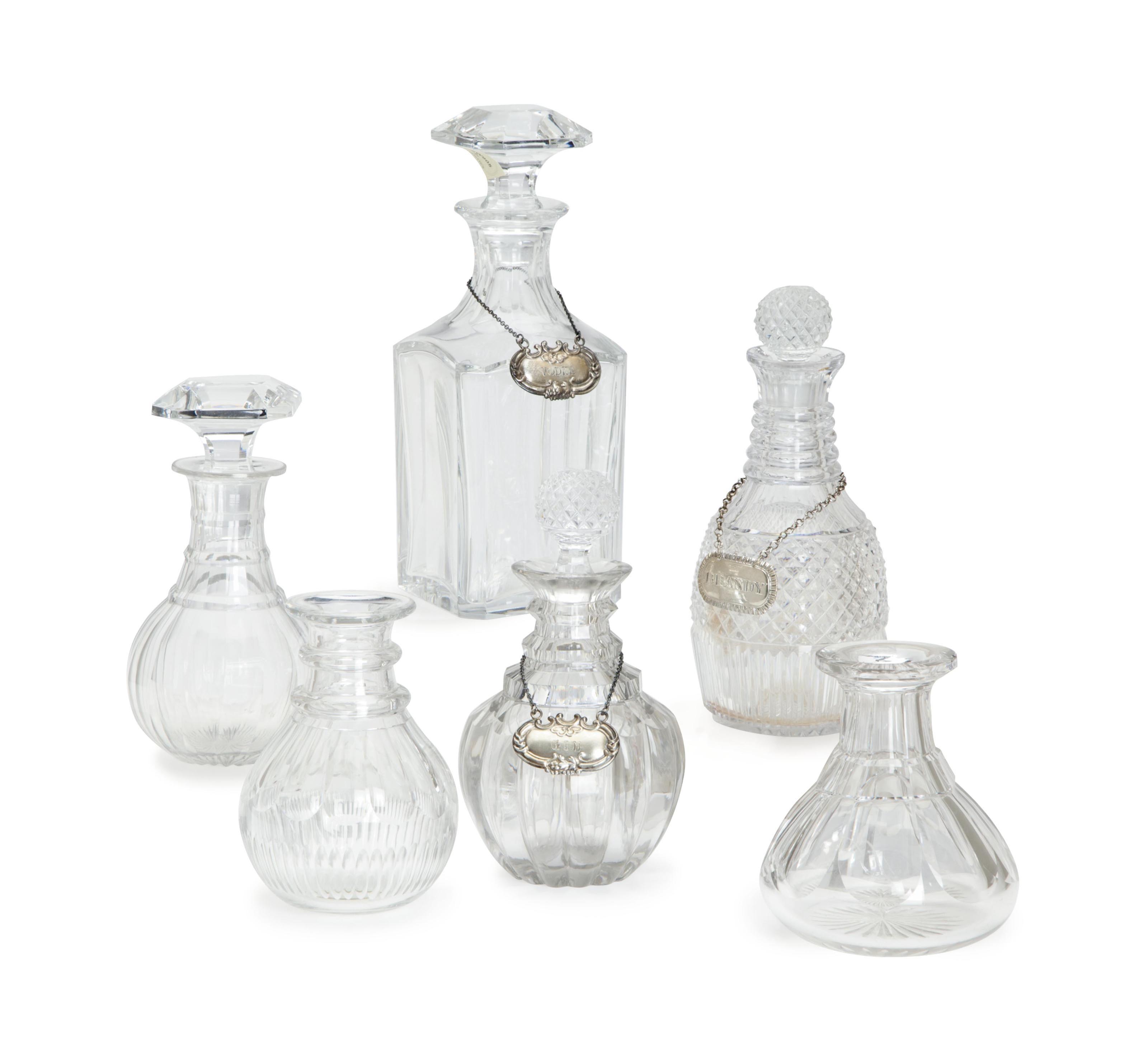 THIRTEEN CUT GLASS DECANTERS, FIVE STOPPERS, A SEAL, AND THREE SILVER