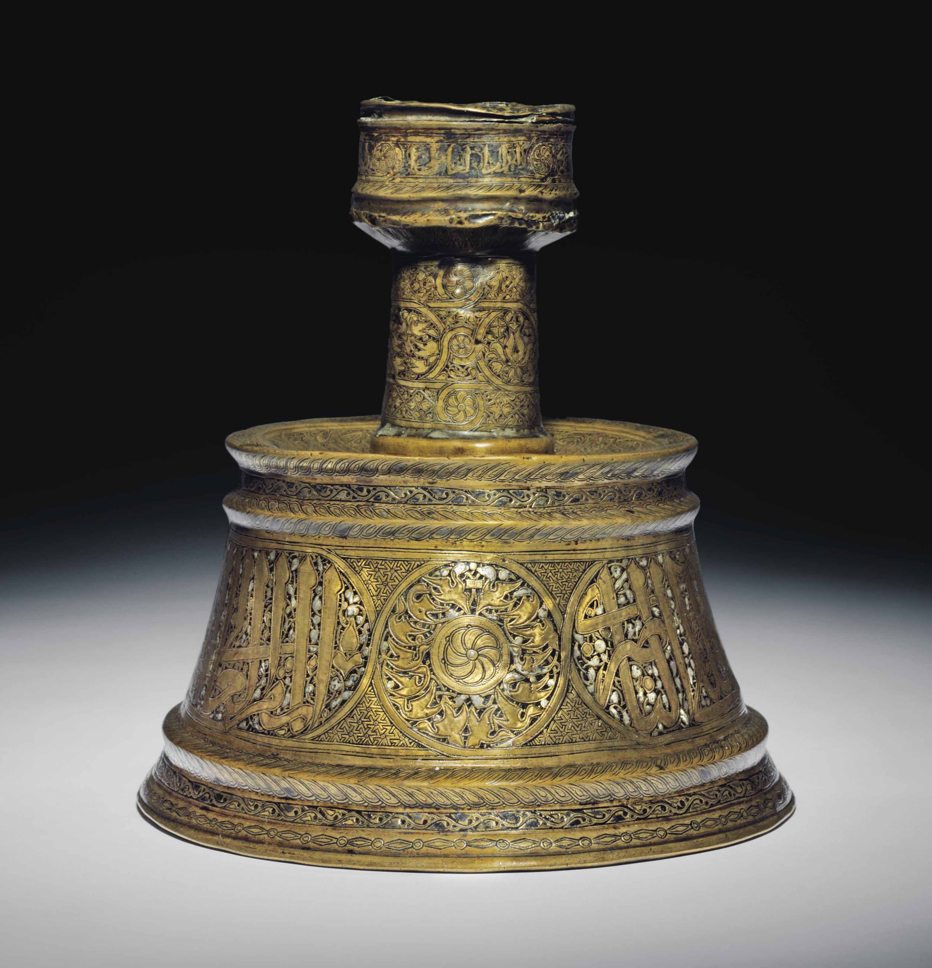 A MAMLUK GOLD AND SILVER INLAID BRASS CANDLESTICK , PROBABLY SYRIA