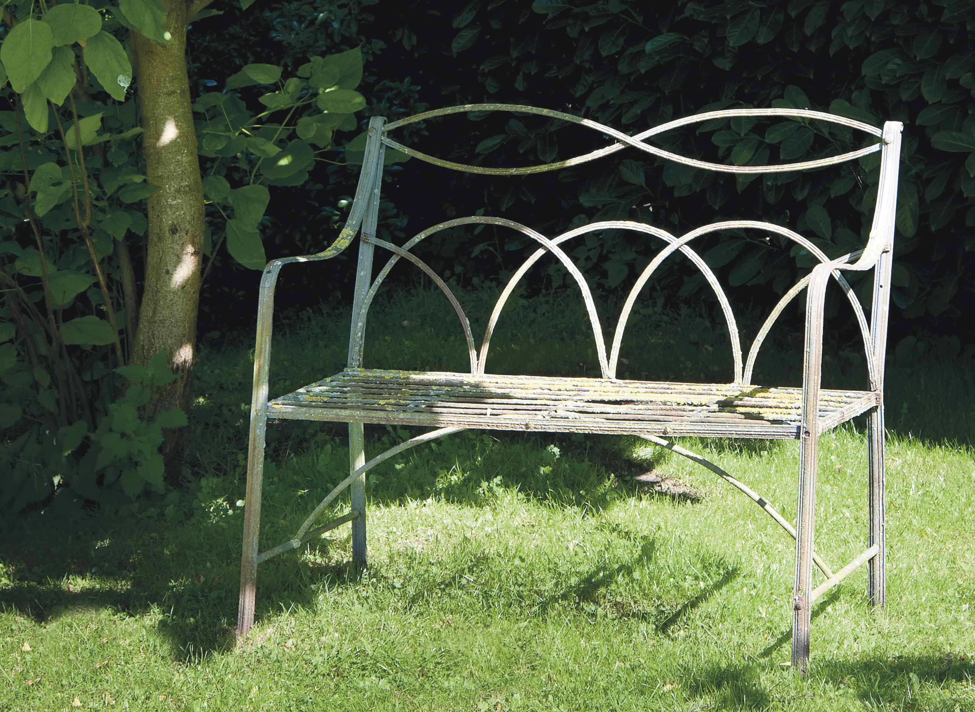 A WHITEPAINTED WROUGHTIRON TWO SEAT GARDEN BENCH
