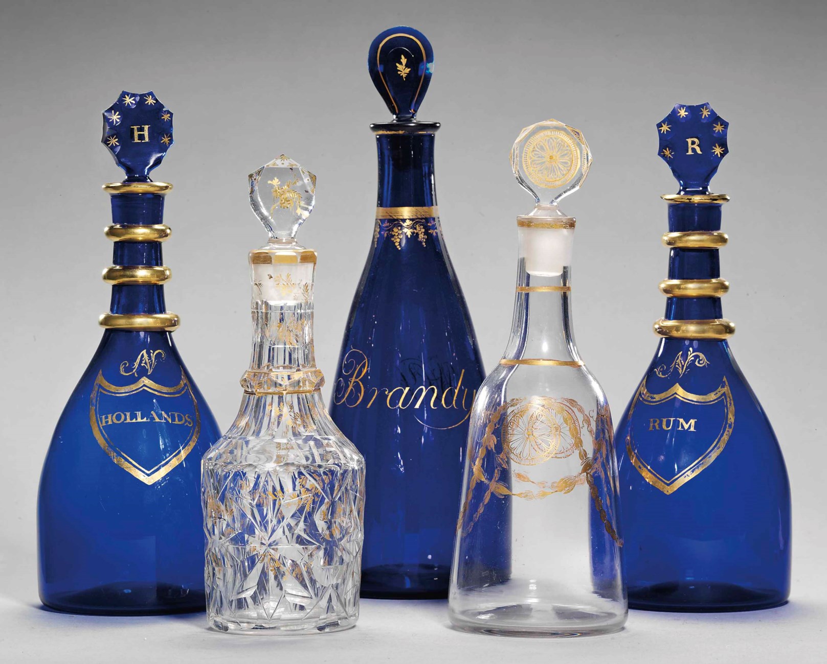 THREE ENGLISH BLUEGLASS DECANTERS AND STOPPERS AND TWO GILT DECANTERS