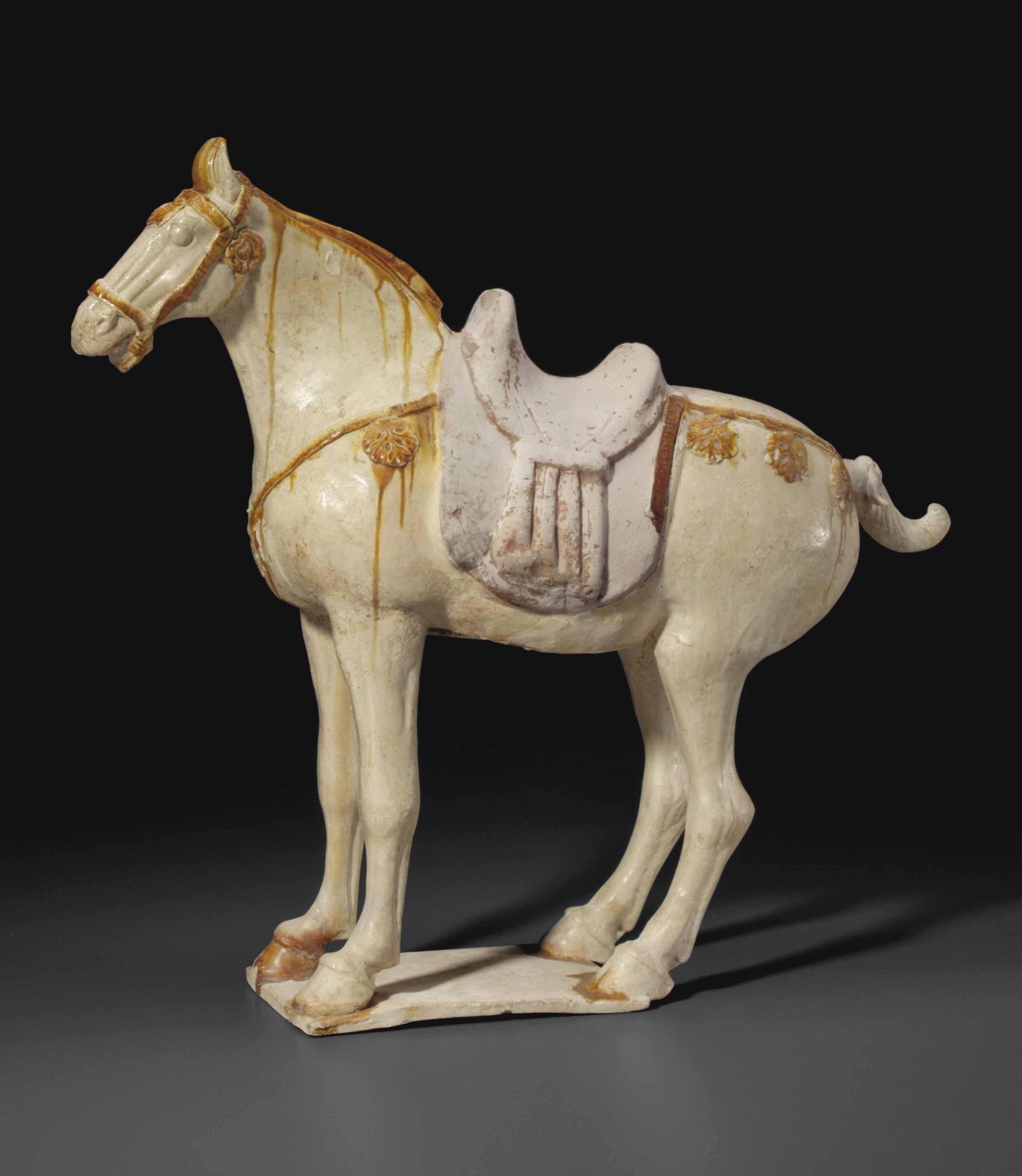 AN AMBER AND CREAMGLAZED FIGURE OF A CAPARISONED HORSE , TANG DYNASTY