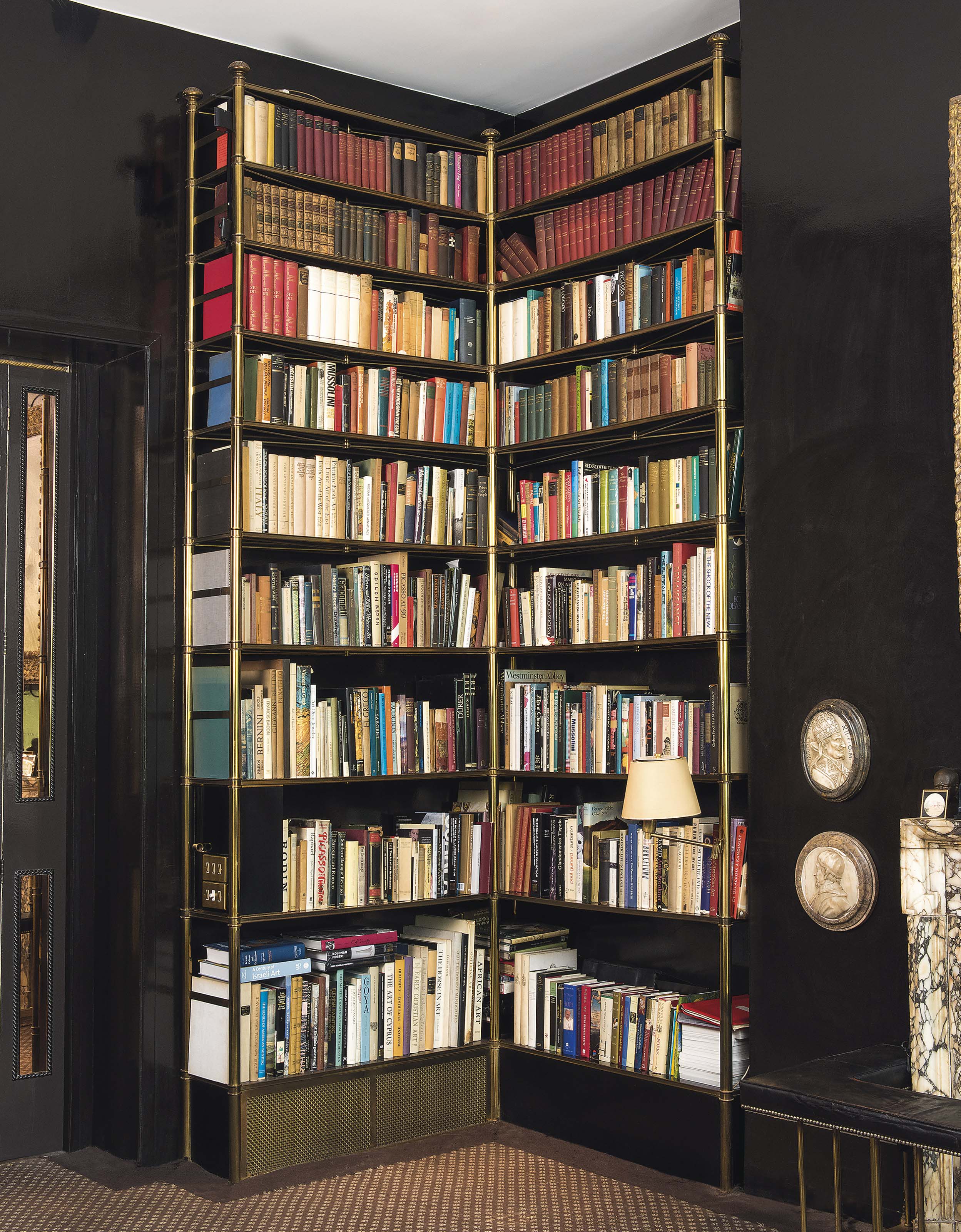 A LACQUEREDBRASS CORNER BOOKCASE , DESIGNED AND SUPPLIED BY GEOFFREY