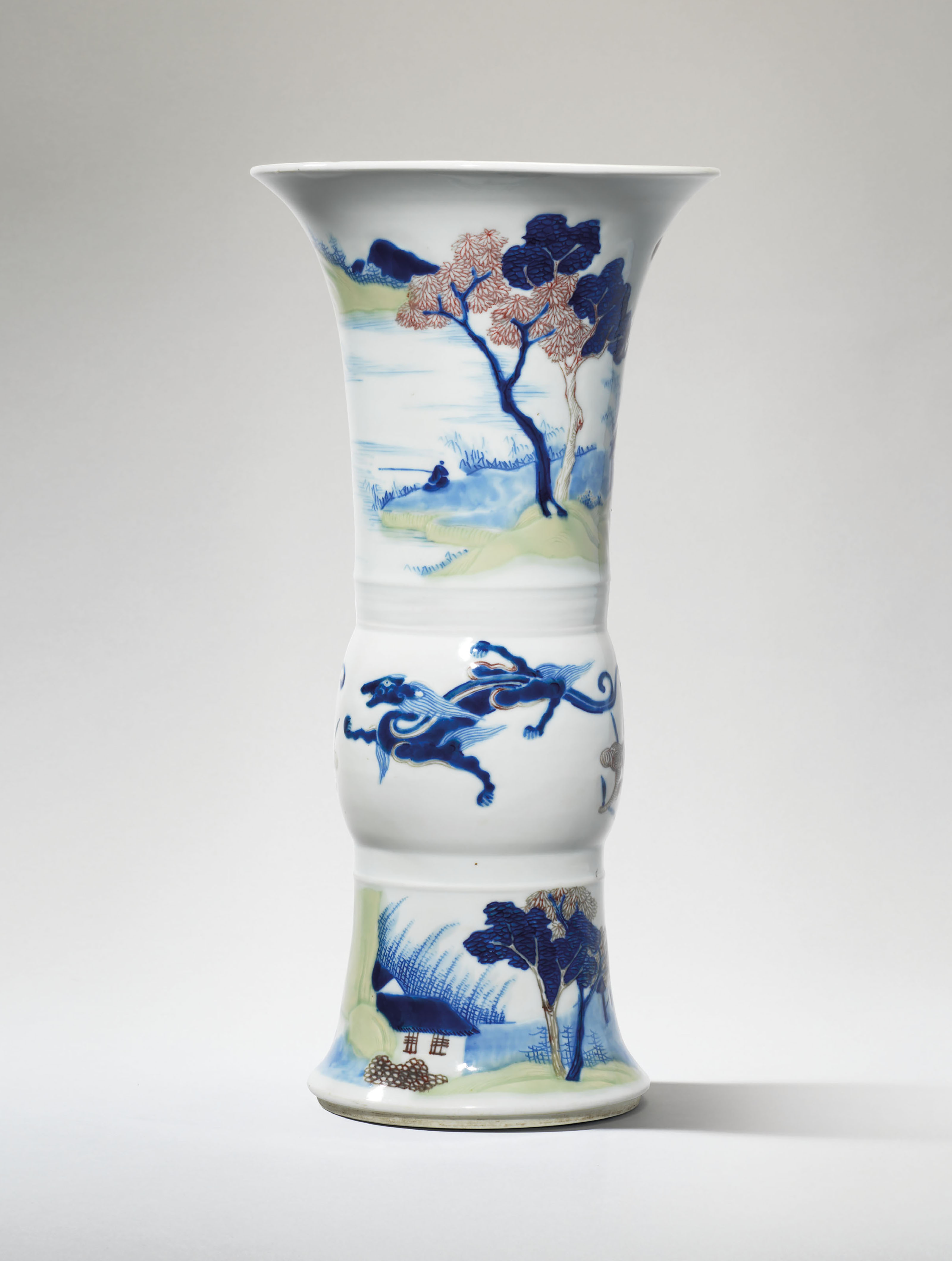 AN UNDERGLAZEBLUE, COPPERRED AND CELADONGLAZED CARVED BEAKER VASE