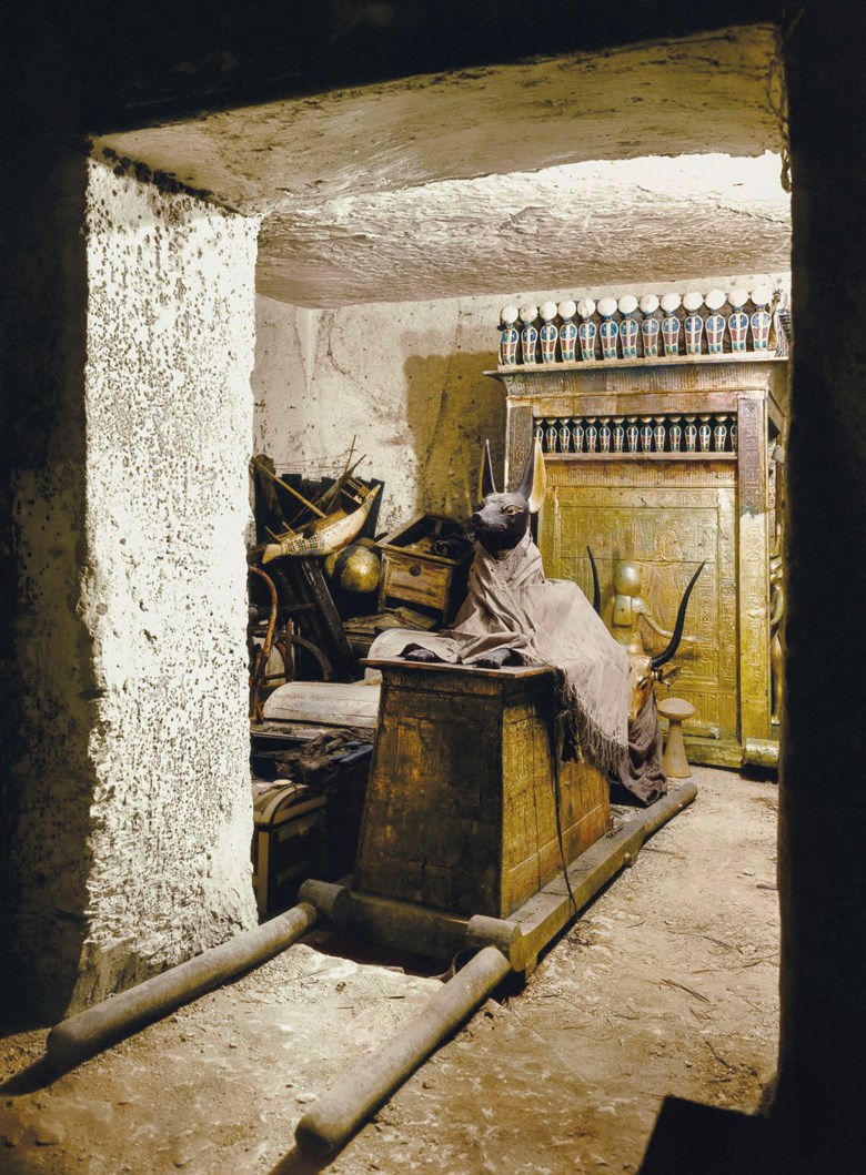 A colourised image of a photograph taken by Harry Burton in October 1926 showing the treasury of Tutakhamen’s tomb, with a statue of Anubis on a shrine with pallbearers’ poles. Photo Burton photograph 1169. © Griffith Institute, University of Oxford. Colourised by Dynamichrome