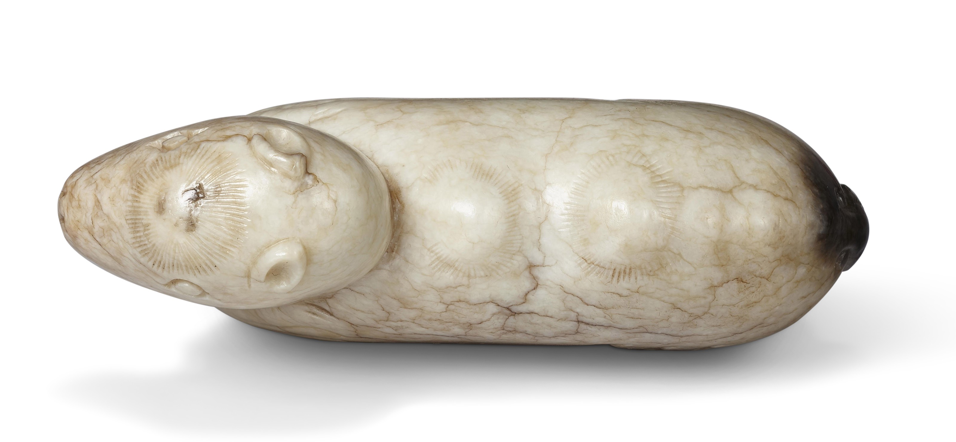 A 'CHICKEN BONE' JADE FIGURE OF A RECUMBENT CAMEL, CHINA, MING
