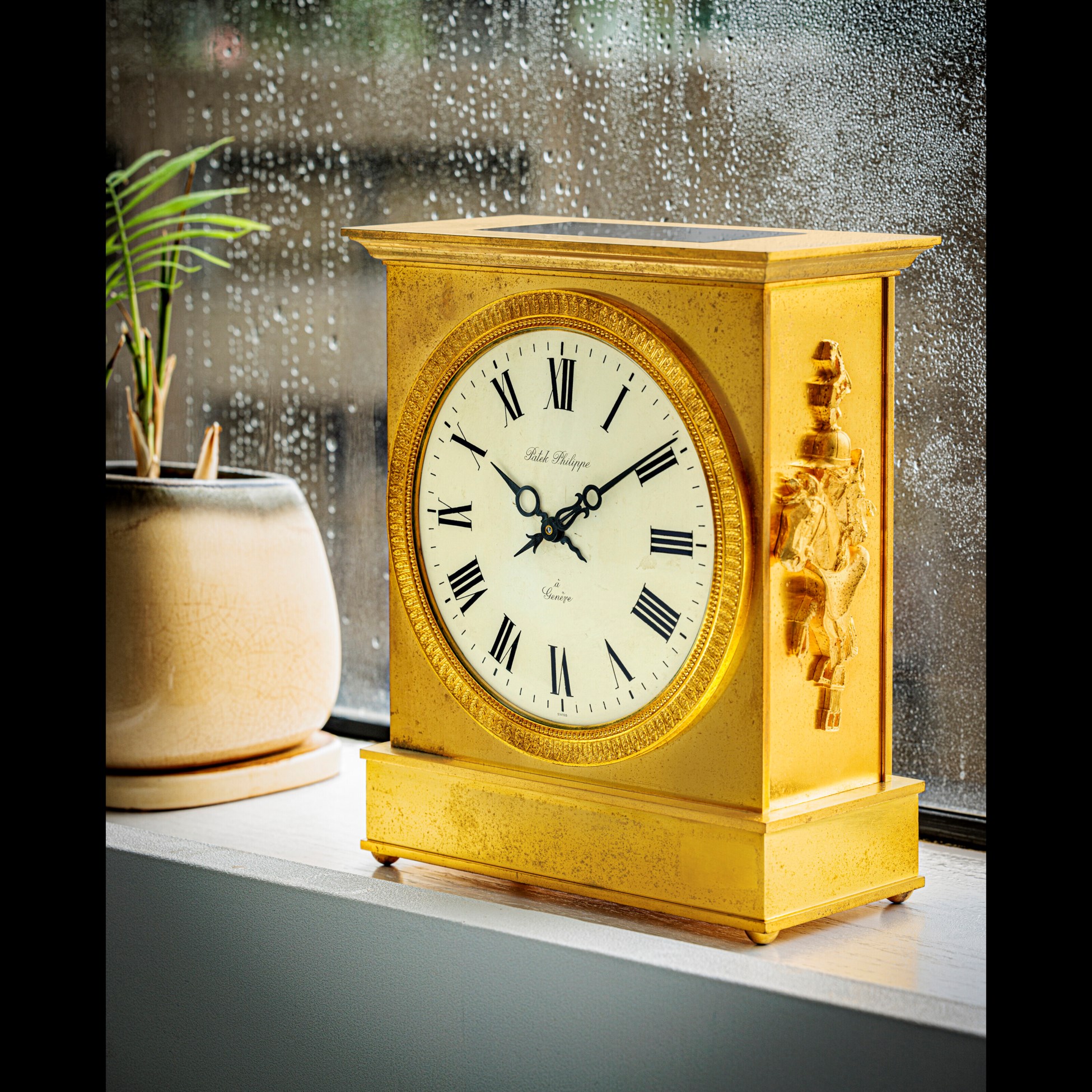 PATEK PHILIPPE. A GILT BRASS SOLARPOWERED DESK CLOCK WITH ENAMEL DIAL