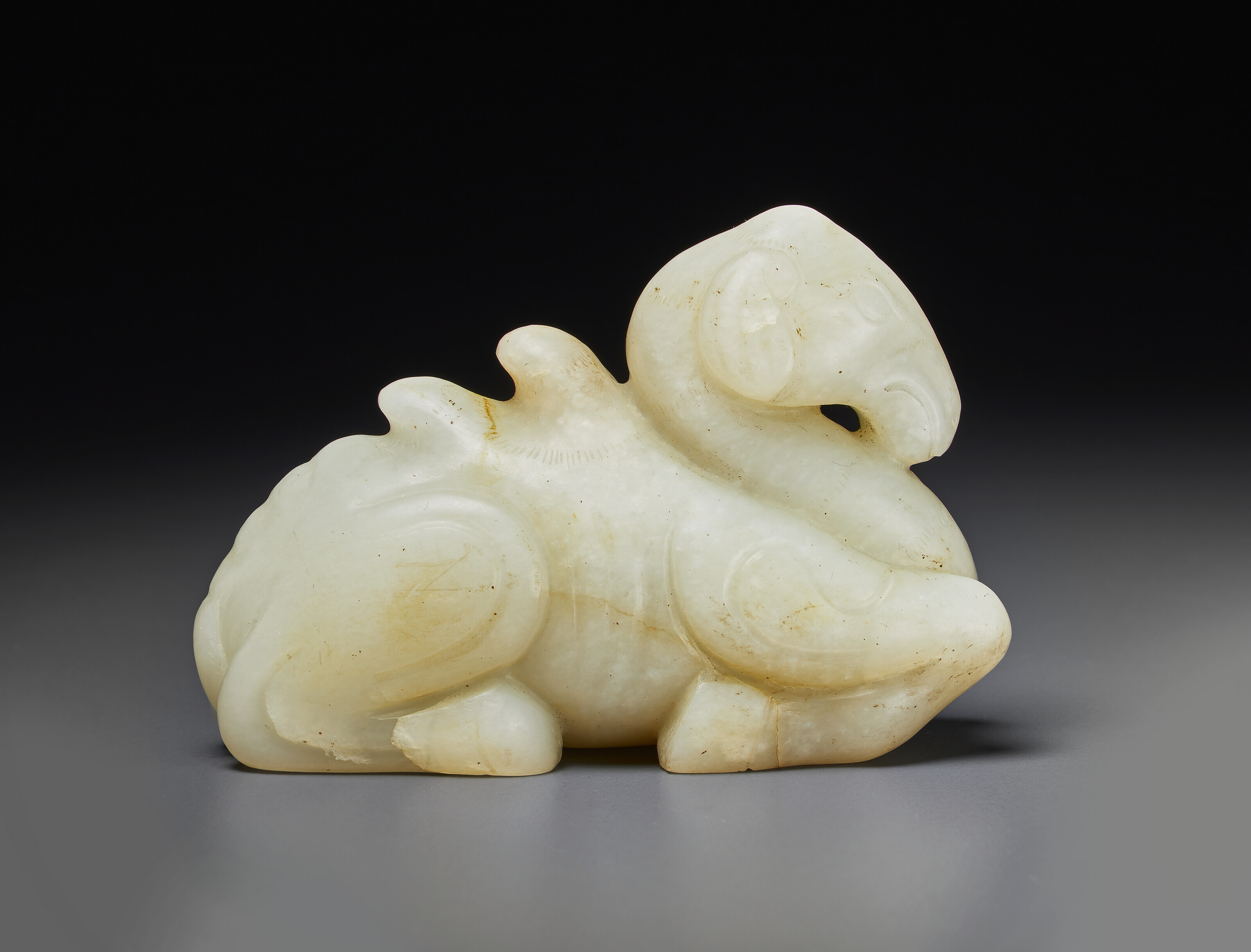 A RARE AND FINELY CARVED WHITE JADE FIGURE OF A MYTHICAL BEAST