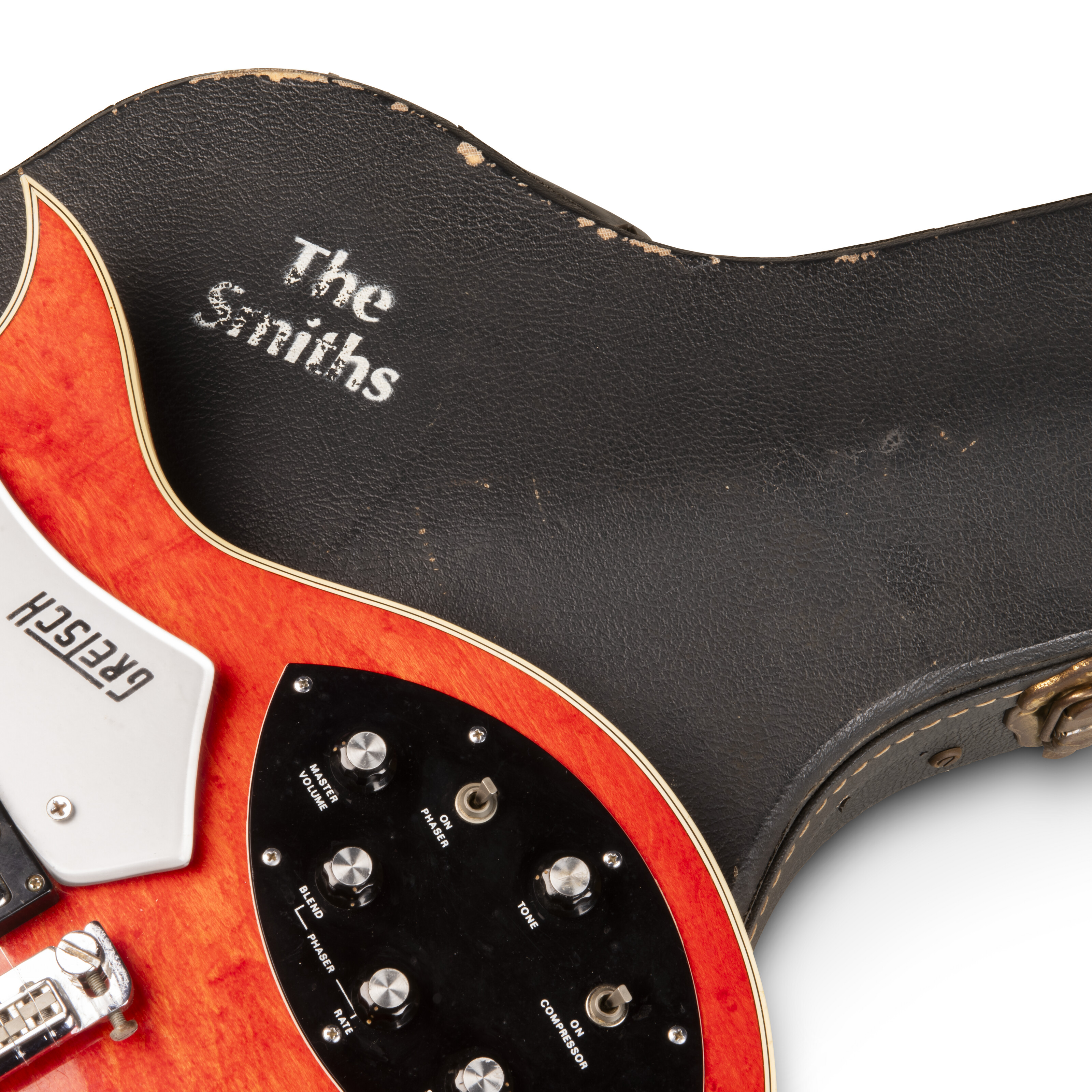 A close-up of Johnny Marr's Gretsch Super Axe, showing the phaser, compressor, volume and tone controls on the front panel of the guitar, and the case stencilled with 'The Smiths'