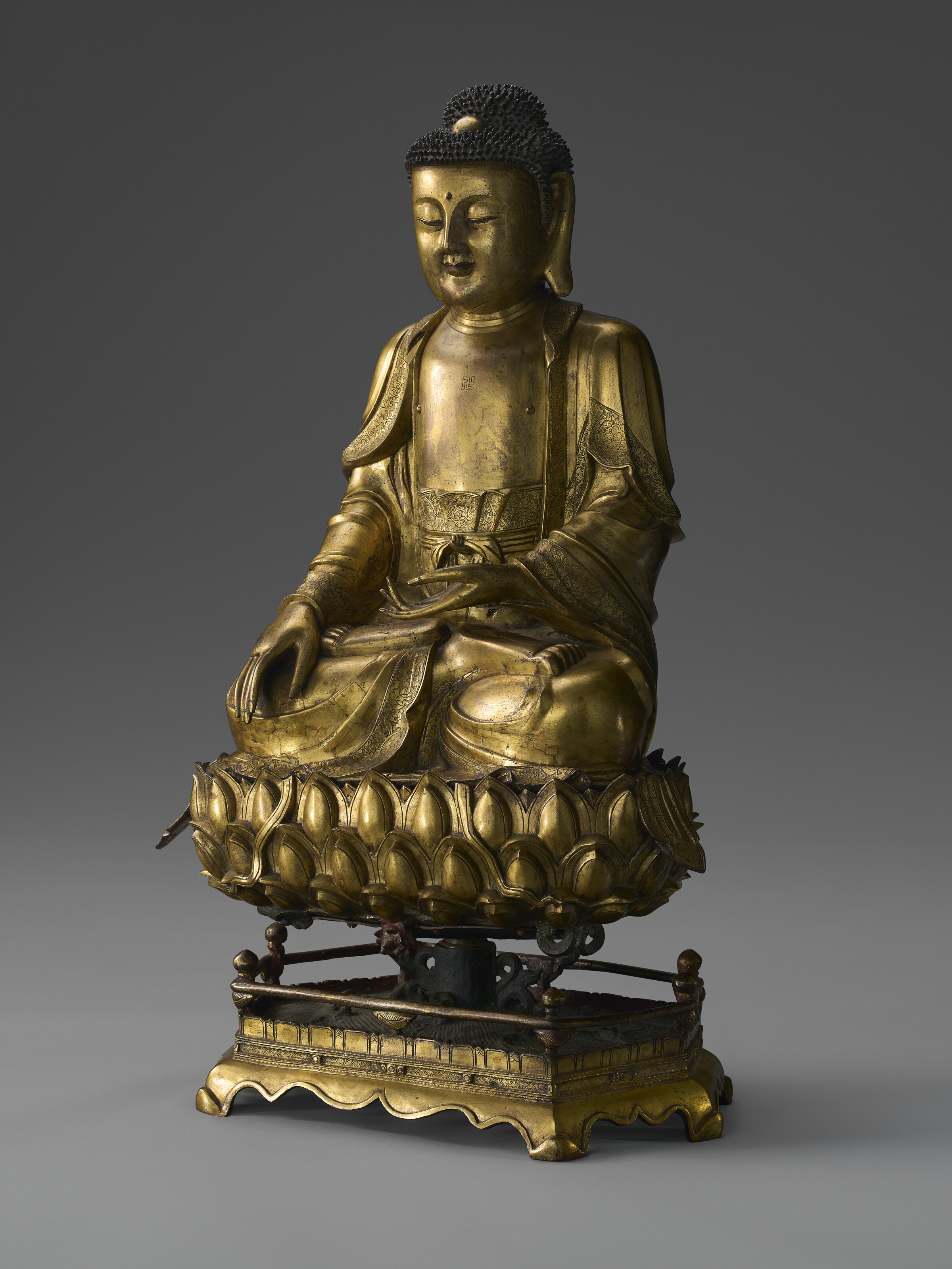 A LARGE GILT-BRONZE FIGURE OF SEATED BUDDHA ON A LOTUS STAND, MING
