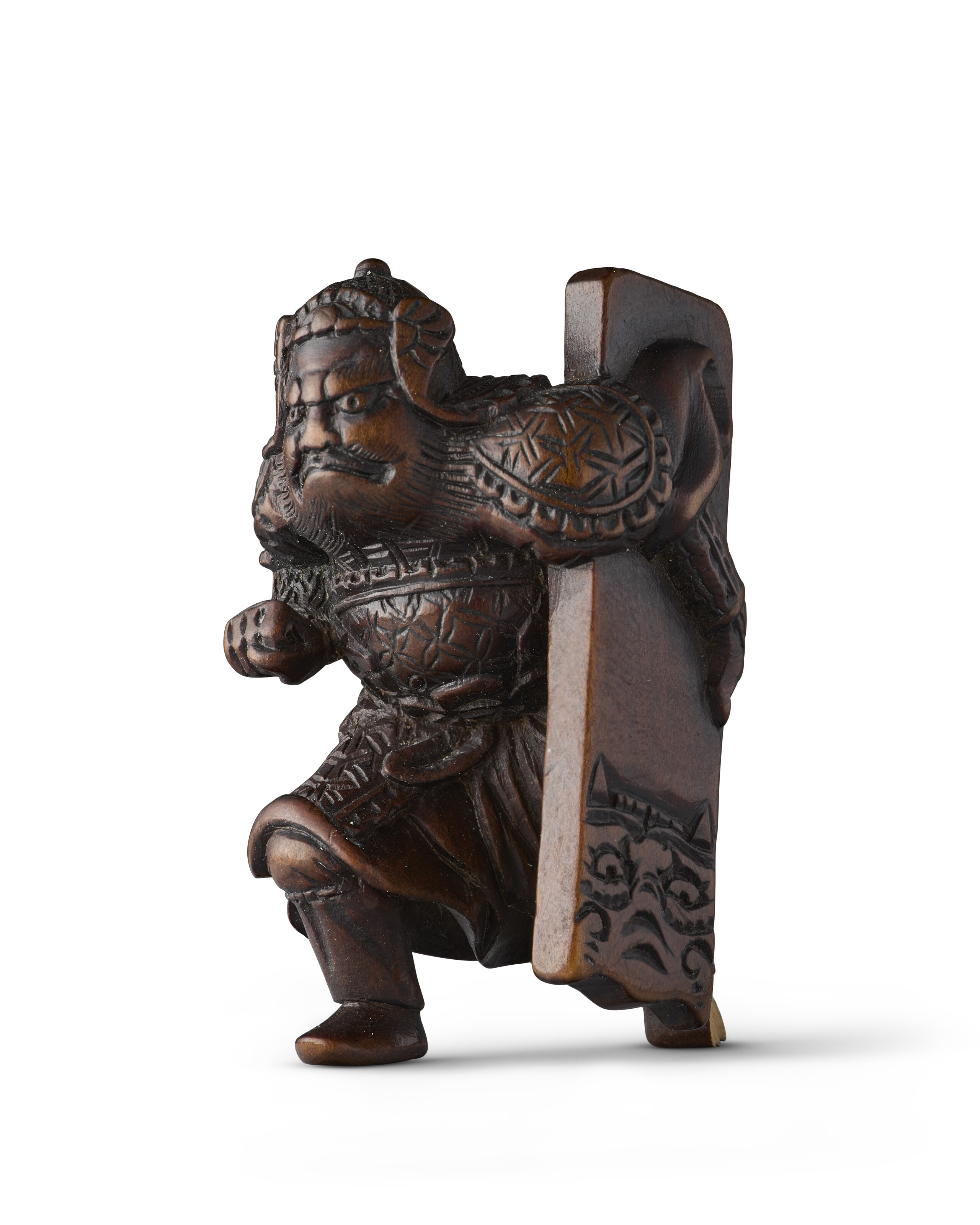 A CARVED WOOD NETSUKE OF HAN KAI (FAN KUAI) CARRYING A SHIELD