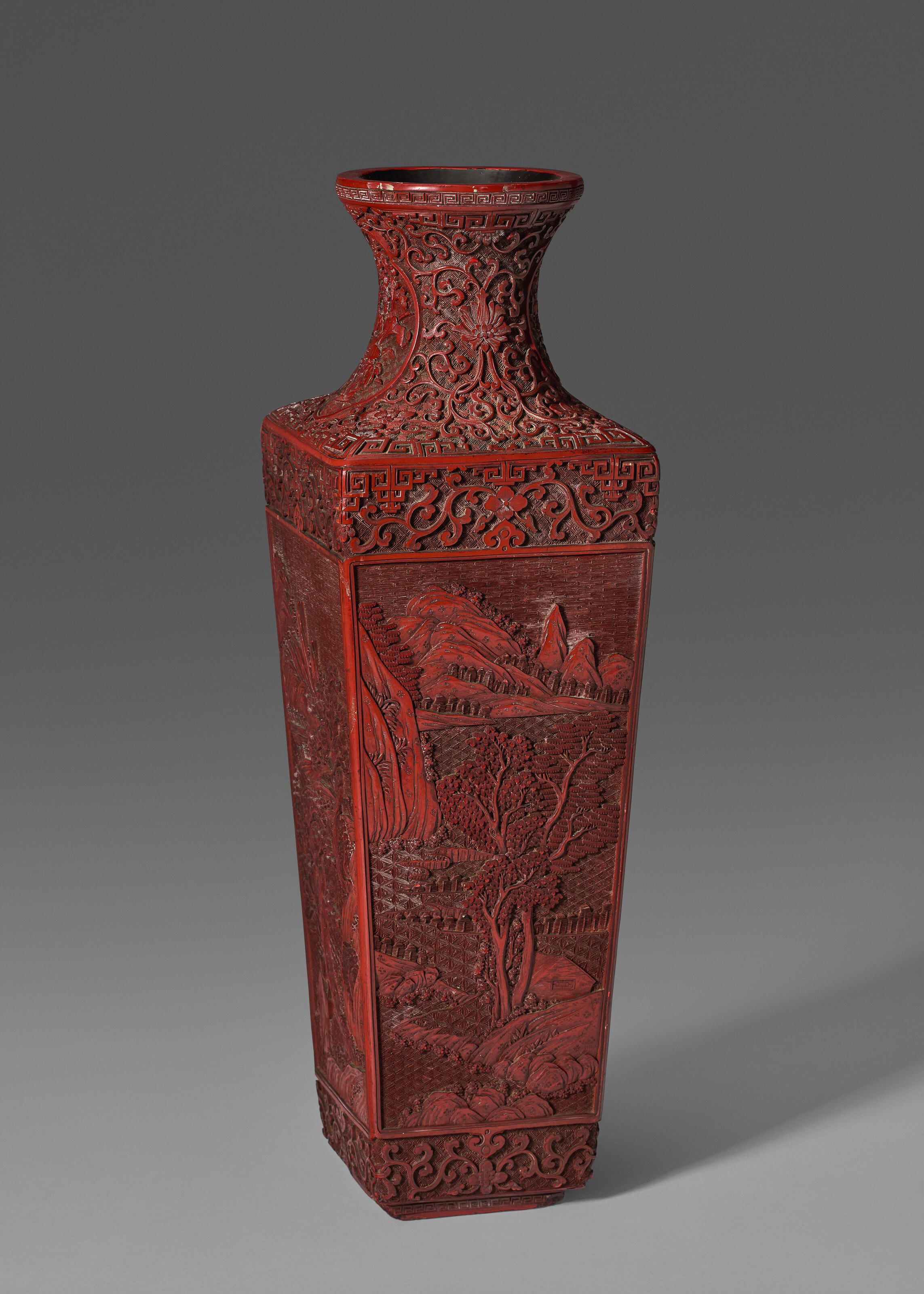 A LARGE CARVED RED LACQUER FACETED 'LANDSCAPE' VASE