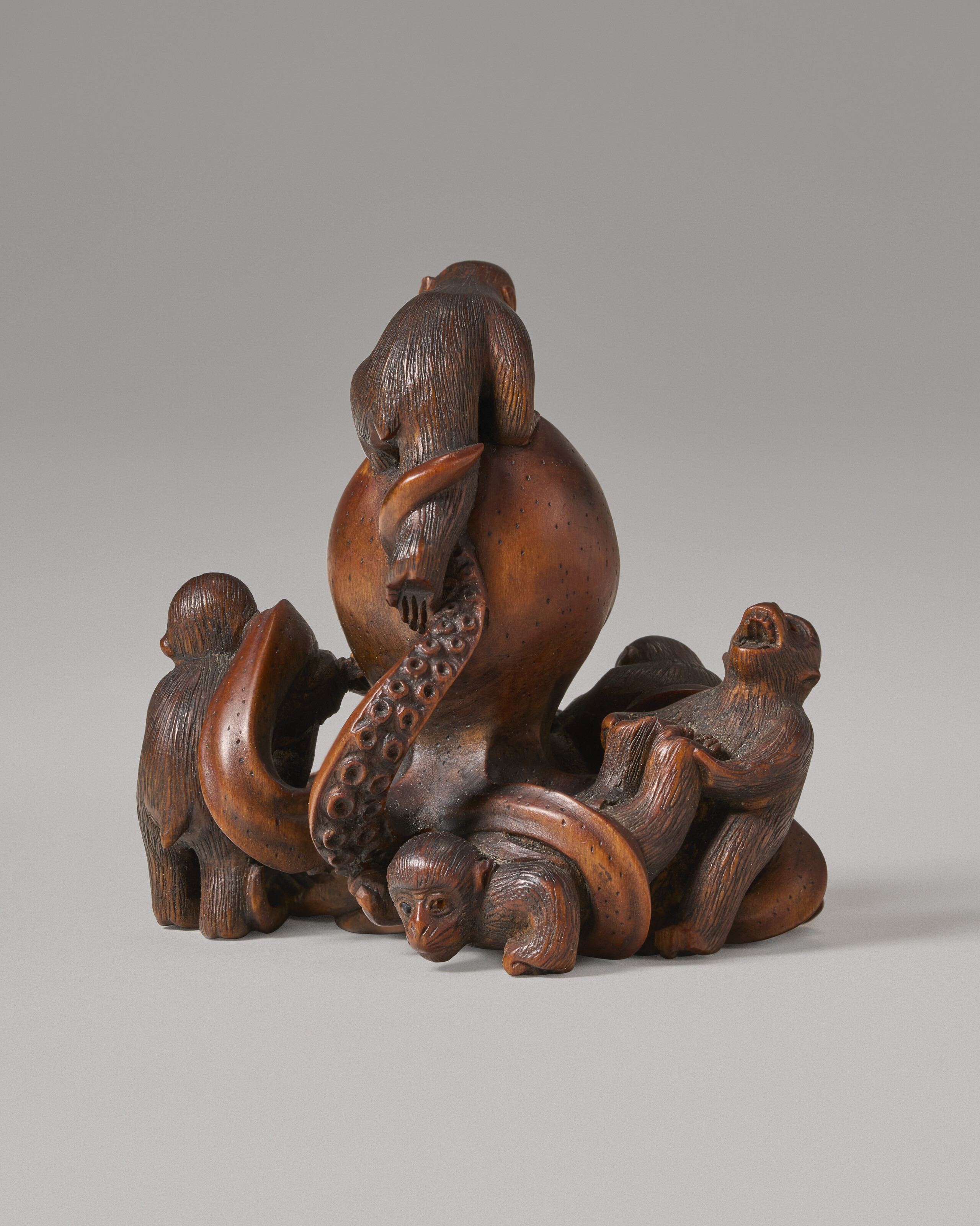 A CARVED WOOD MINIATURE SCULPTURE (NETSUKE) OF OCTOPUS AND MONKEYS