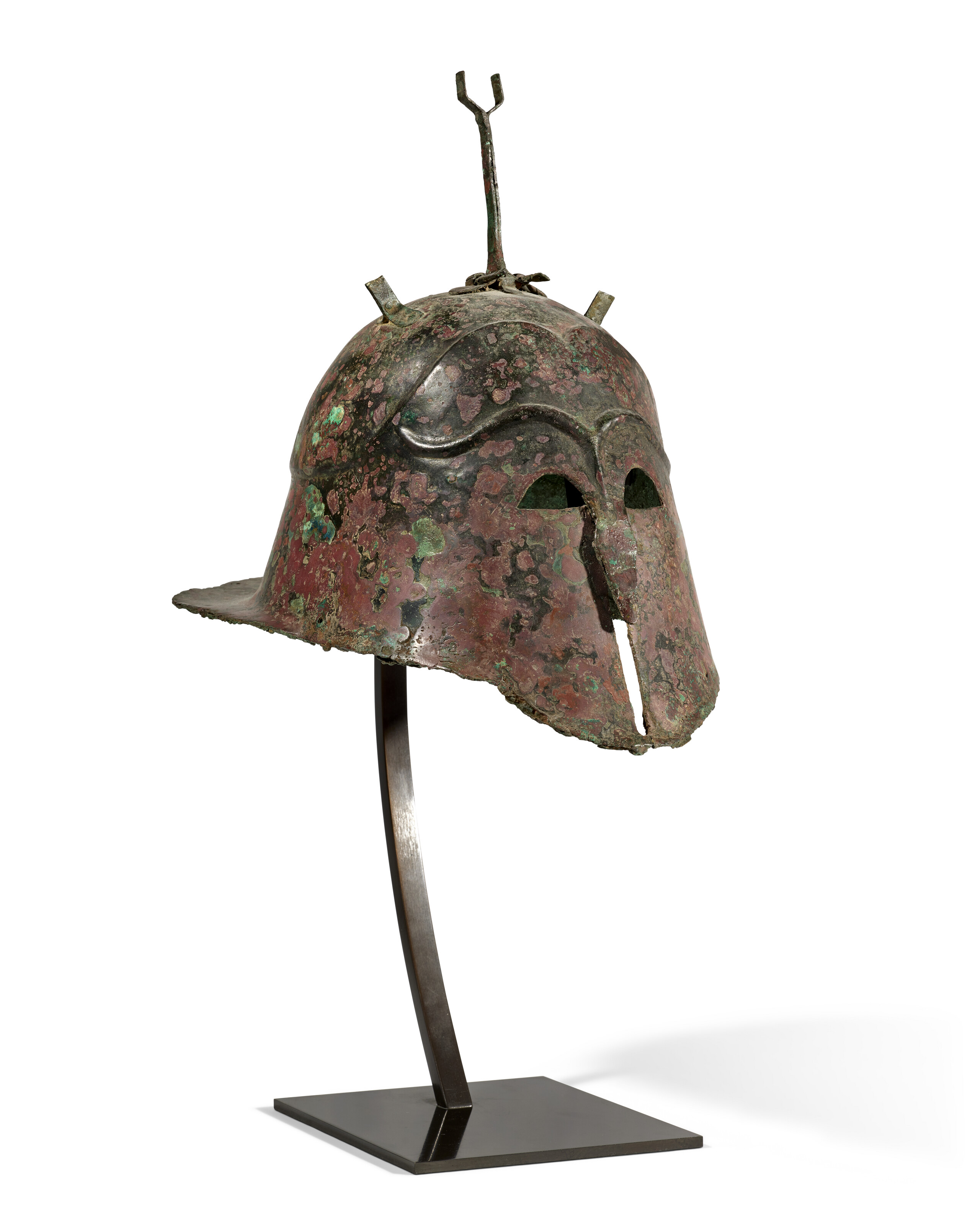 A greek bronze Apulo-Corinthian helmet, Magna Graecia, late Archaic to early Classical period, circa 525-475 B.C., together with a Greek bronze greave or ankle-guard, circa 6th-4th century B.C. (not shown), offered in Collections: incluant la succession de Francoise Lambert, vendue au profit de la Societe des Amis de Versailles, until 1 October 2026 at Christie's Online