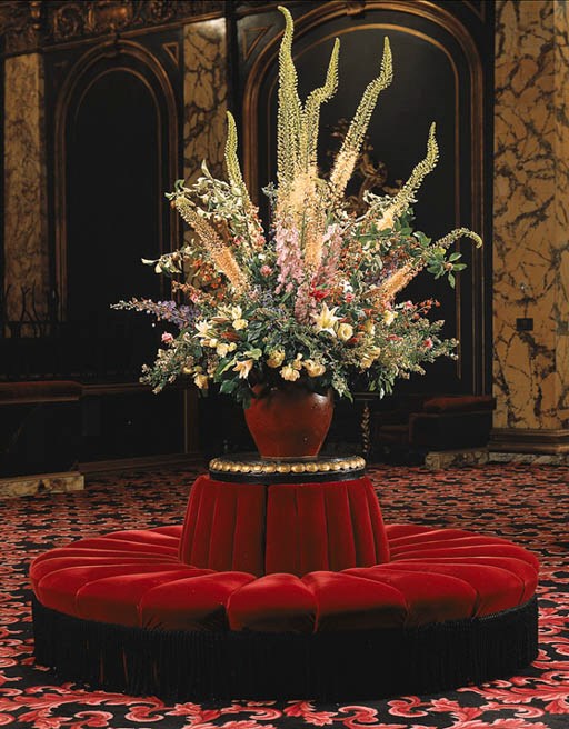 AN UPHOLSTERED BANQUETTE WITH PARCEL-GILT AND LAMINATED, EBONIZED WOOD PLATEAU