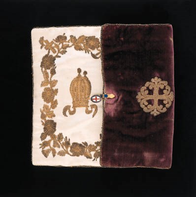 THE MOST NOBLE ORDER OF THE GARTER, a Prelate's Purse, circa 1830, 115 x 150mm., purple velvet with gilt wire border, the front with a Shield, the back with a Cross, both in gilt wire; the interior in white satin, the front decorated with a Bishop's Mitre enclosed by a religious and floral motif, the back decorated with a Goat's Head upon a Coronet enclosed by a floral motif, both in gilt wire, the catch, in gold and enamel, featuring the Cross and Legend of the Order, minor enamel damage to the latter, very good condition, rare