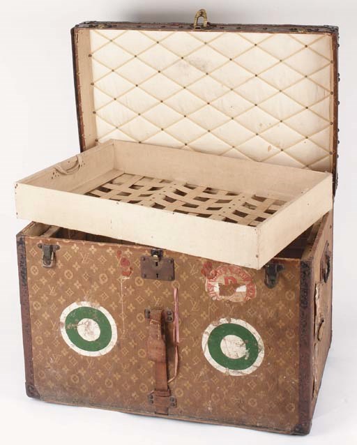 A Louis Vuitton hat trunk, covered in LV monogram canvas and bound in iron and leather with wooden banding, monogrammed K.D on the sides, with green and white target shaped owner marks on front and top, the lock numbered 021879, with keys and leather strap, the interior with white ribbon lattice lid and fitted with two webbed trays, labelled Louis Vuitton Paris London 155285--29 1/2 x 19 x 21 1/2in. (75 x 48 x 55cm.), circa 1905, some wear