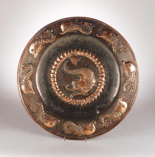 A copper charger decorated with grotesque dolphins