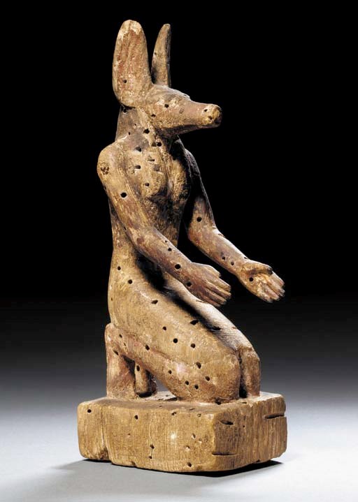 AN EGYPTIAN WOOD FIGURE OF ANUBIS