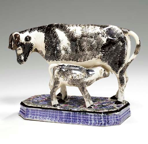 A BRITISH PEARLWARE MODEL OF A COW NURSING HER CALF