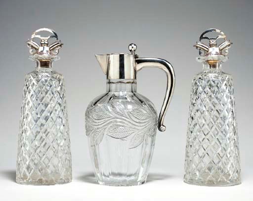 A PAIR OF CUT GLASS DECANTERS WITH SILVER STOPPERS AN A CLARET JUG,