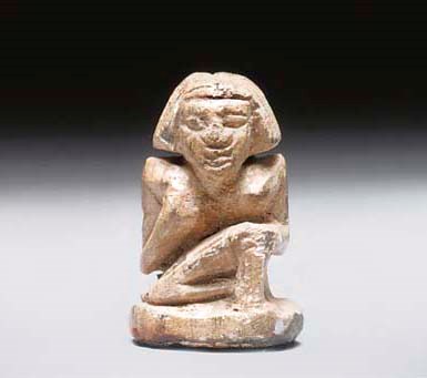 AN EGYPTIAN STEATITE STAMP SEAL IN THE FORM OF A SEATED MALE FIGURE