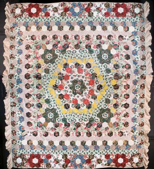 A good large patchwork coverlet, Sunburst variation, pieced from large hexagons, predominantly of chintz, two sides with a deep frill border--94 x 102in. (240 x 260cm.), mid 19th century