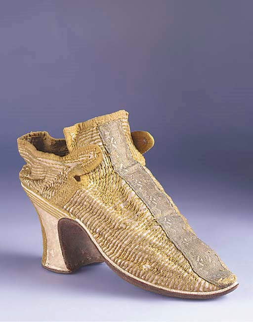 A single lady's shoe, of ivory satin, the uppers embroidred in olive green silks in chain stitch, the 3in. (8cm.) covered heel applied with narrow strips of braid in angular form, with white kid rand and upturned toe with rounded point, the vamp and heel applied with silver metal braid, English, circa 1730