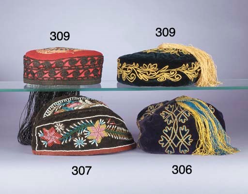 A smoking cap of red facecloth, the rim chainstitched in black silks, the crown with a Russian-style motif in coloured wools, with a deep black silk fringe simulating hair, early 20th century; a navy blue velvet smoking cap applied with narrow gold braid and with similar tassel; and two Indian caps, the black velvet applied with metal thread, spangles, purl, coloured foil and imitation pearls, late 19th century