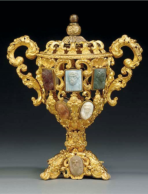 A CONTINENTAL EMBOSSED GILT METAL URN
