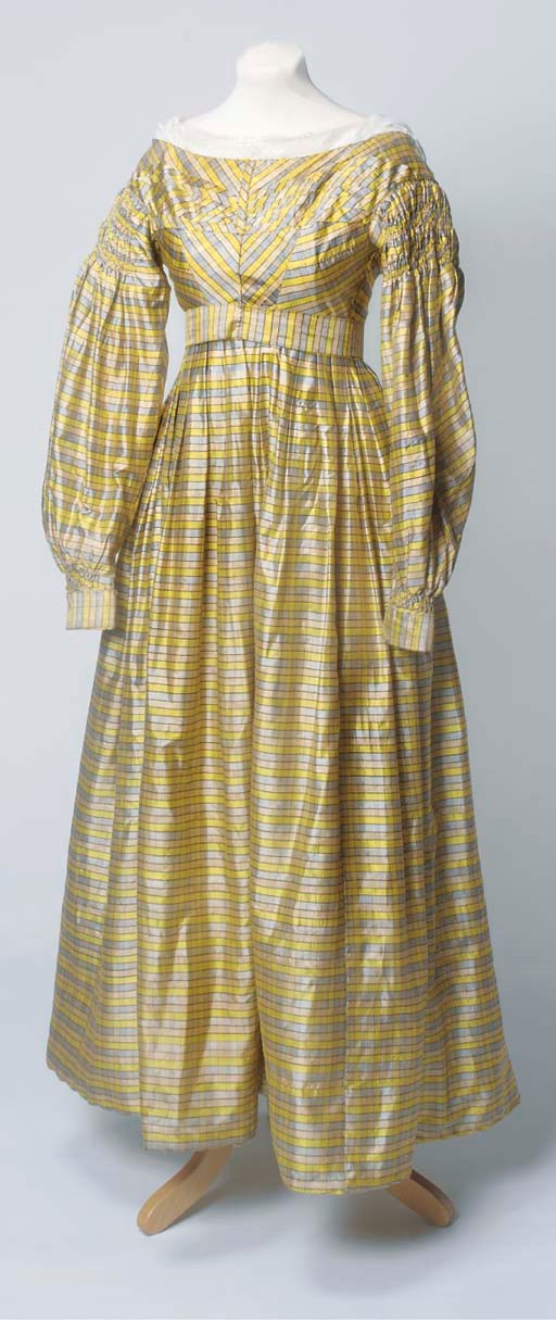 A lady's day dress of yellow, blue and beige checked silk, the high waisted bodice with self-fabric pleating and piping, with  "gigot" sleeves with gathered detailing to the shoulder, the skirt with padding to hemline, fully lined, complete with matching belt and lace trimmed camisole some wear to hemline, circa 1830