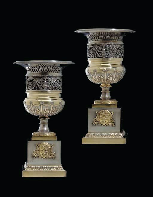 A PAIR OF ITALIAN PARCEL-GILT SILVER URNS ON STANDS